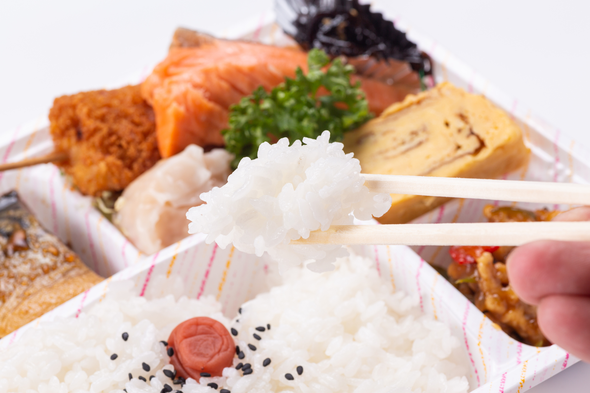 写真: 弁当に入ったお米を箸で取っている様子。米は艶やかなである